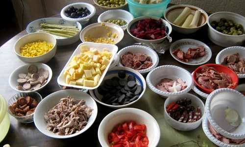 Preparing Guatemalan fiambre, layering the marinated ingredients