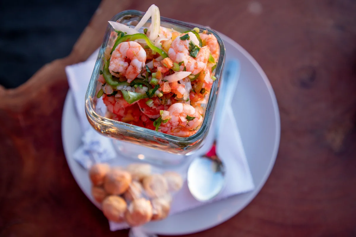 Guatemalan shrimp ceviche in a blue-rimmed glass on a wooden table