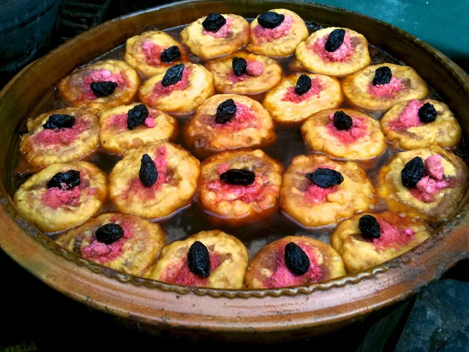 A clay pot of torrejas in syrup, each topped with a prune, at a feria