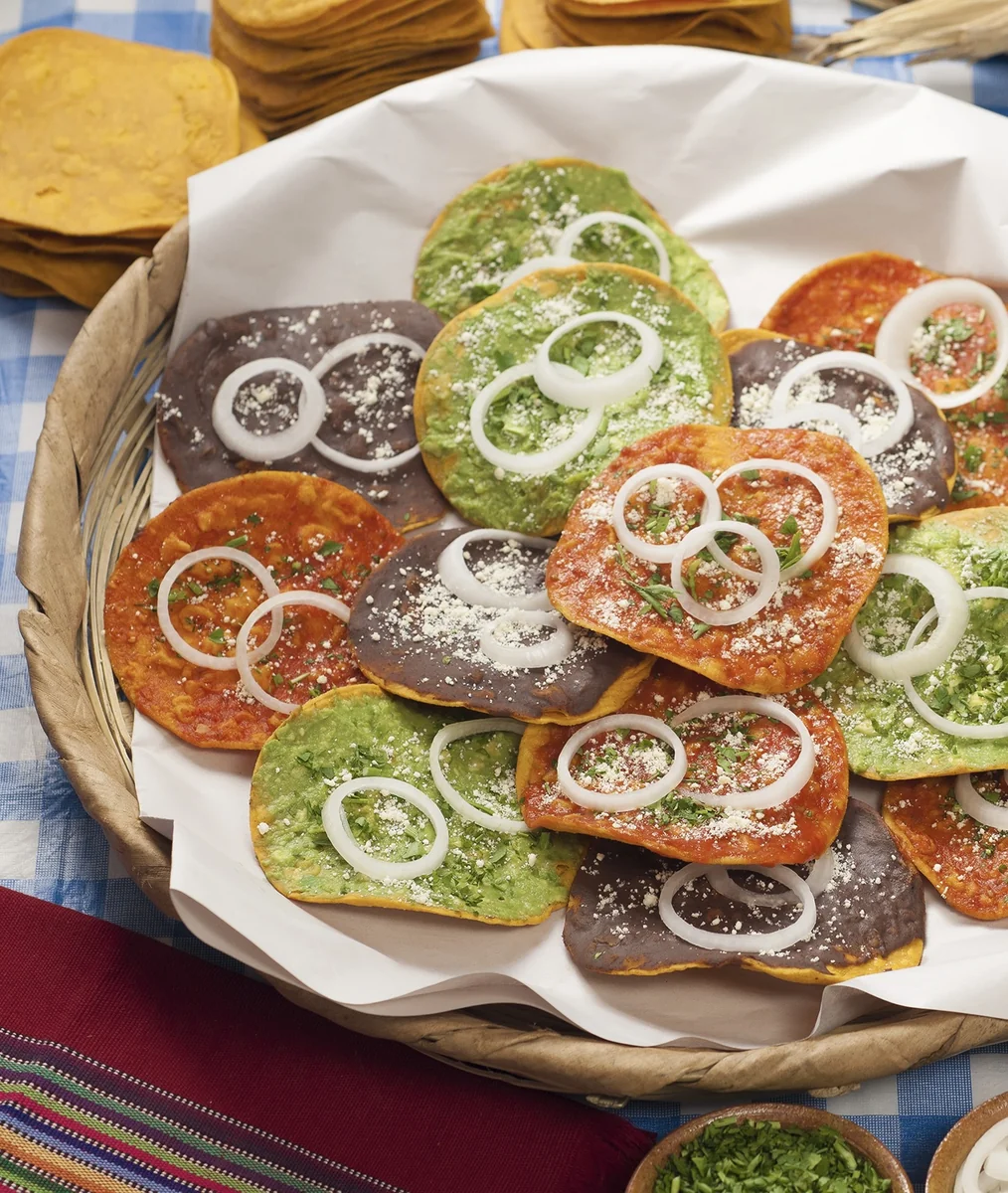 Basket of Guatemalan tostadas with guacamole, black bean, and red salsa toppings served as an appetizer