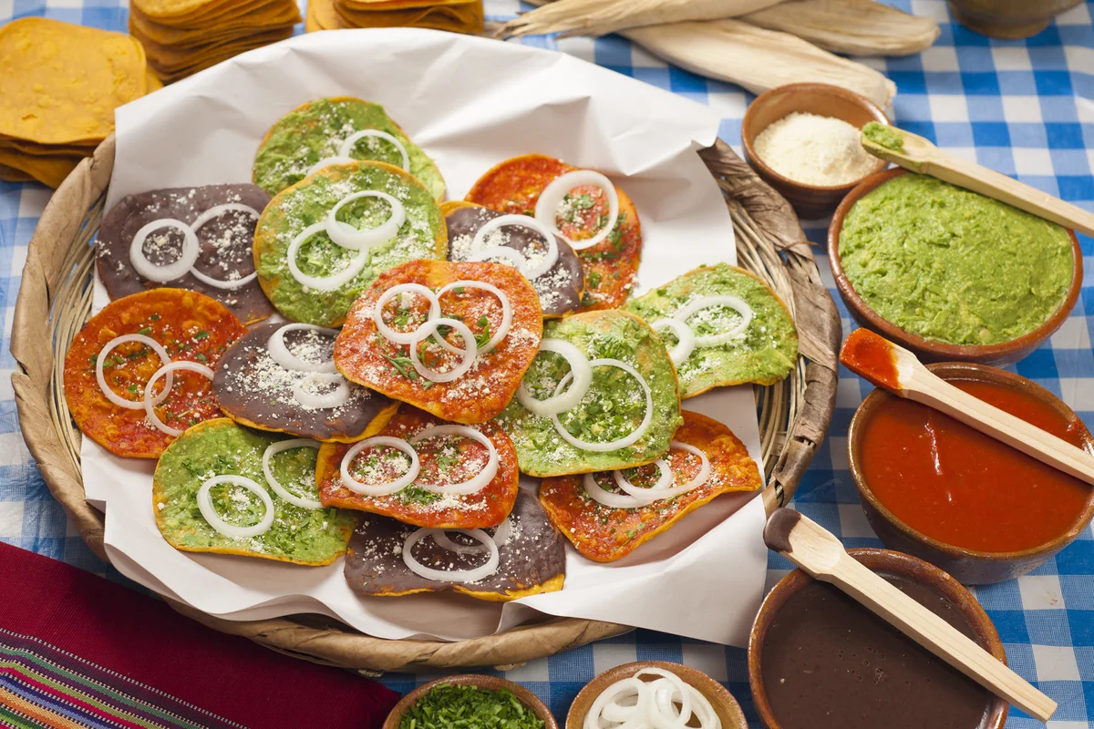 Platter of Guatemalan tostadas with guacamole, black bean, and recado toppings served with side bowls