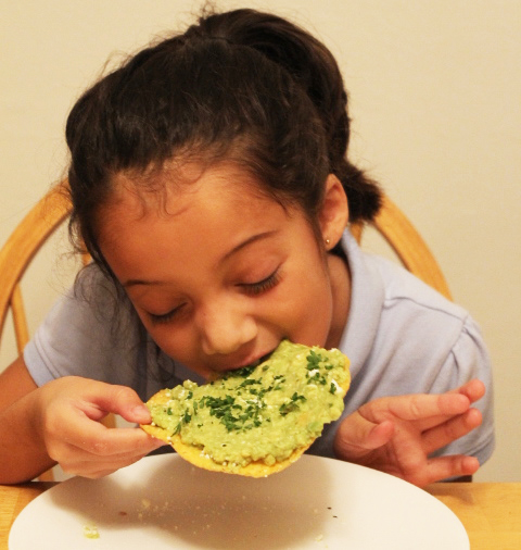 girl eating guacamole tostada