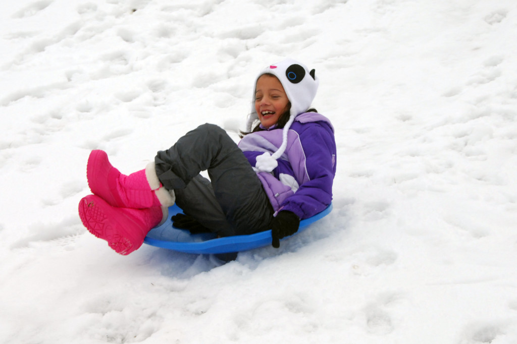 girl sledding in the snow