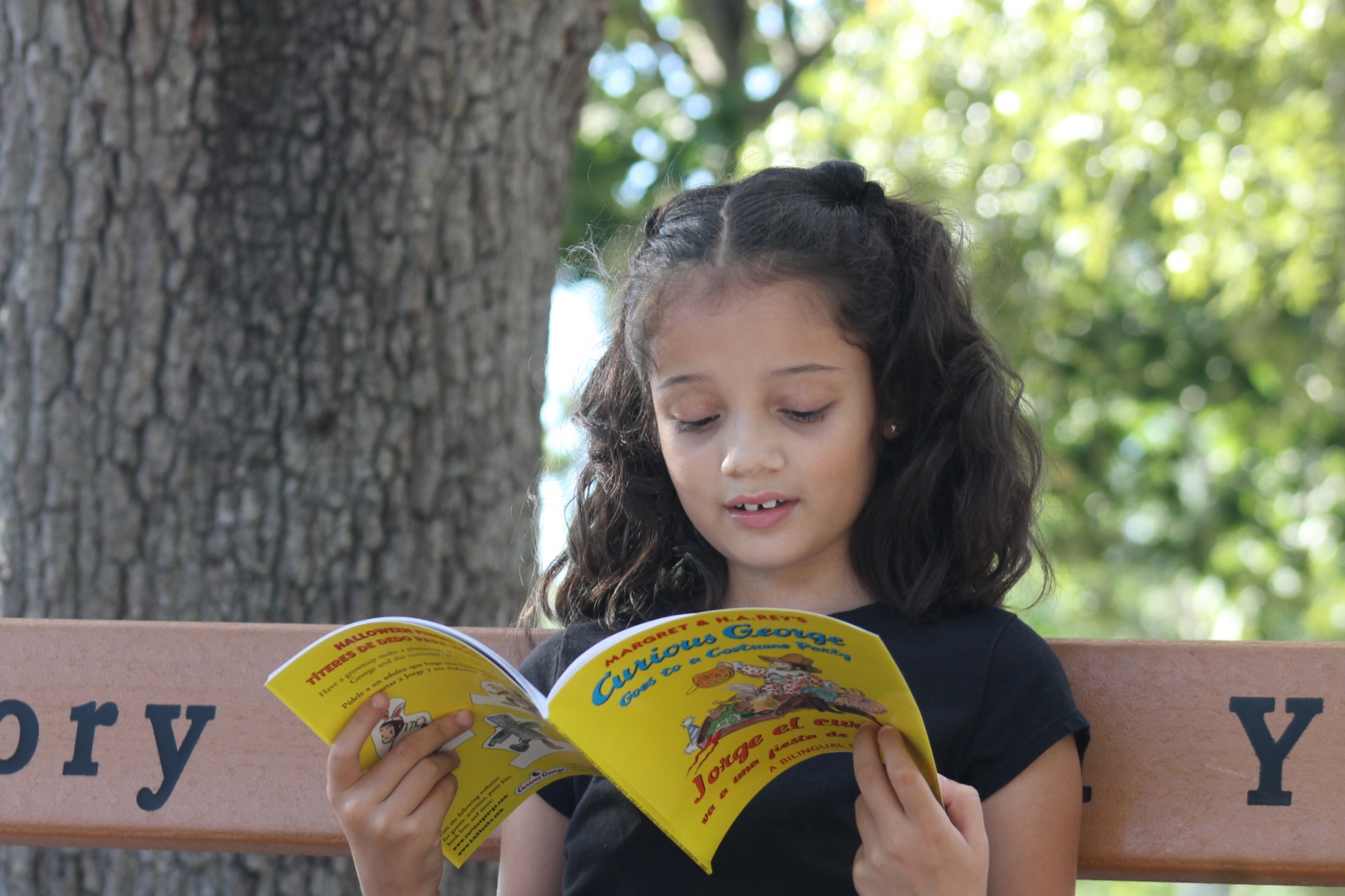 girl reading bilingual Curious George book