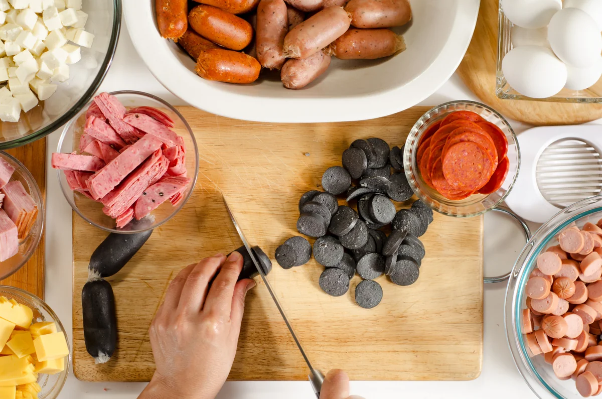 Slicing sausages and cold cuts on a cutting board for fiambre
