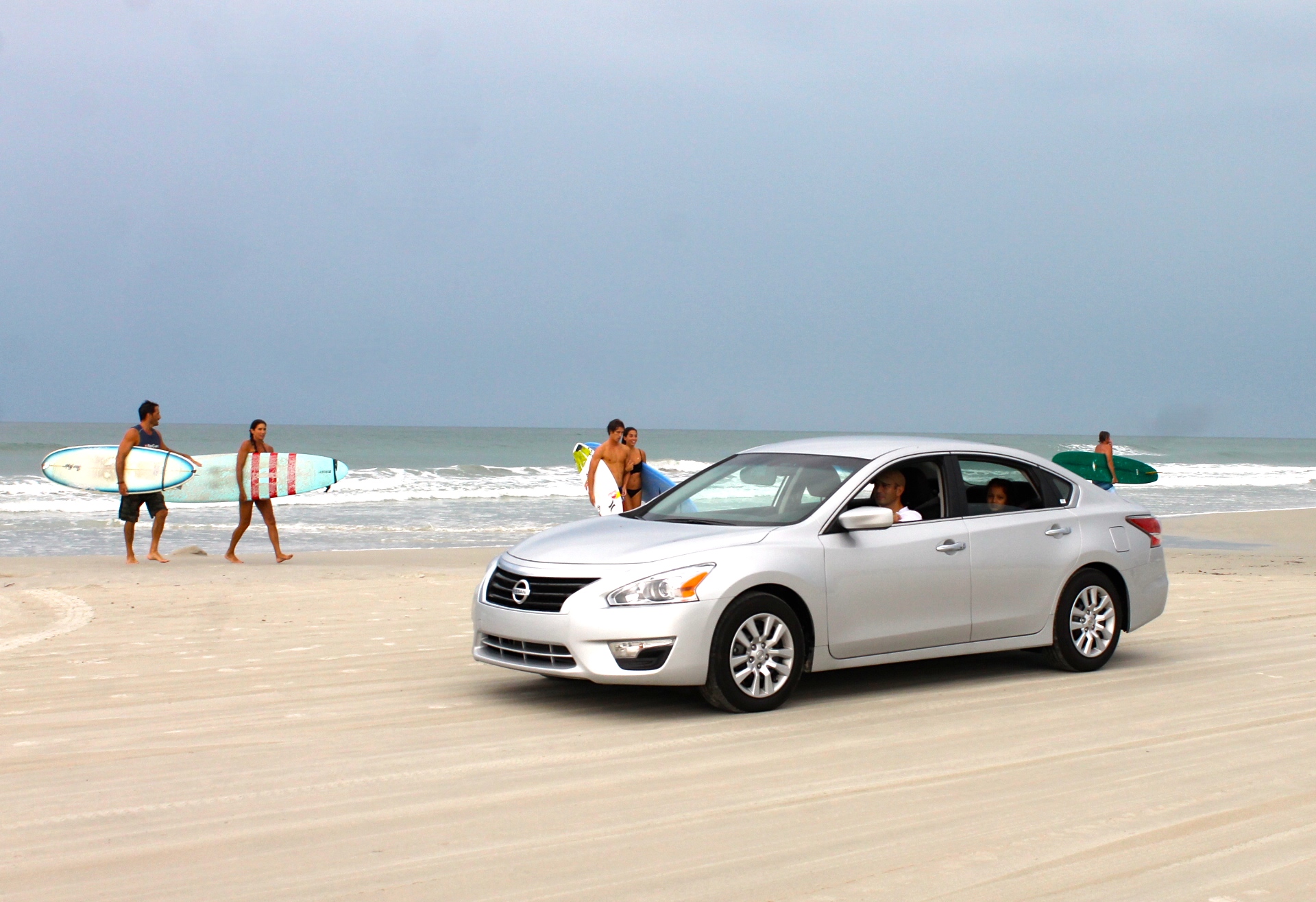 Nissan Altima driving on the beach with surfers