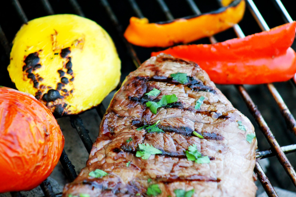 Steak on the grill with mango tomato and peppers onions
