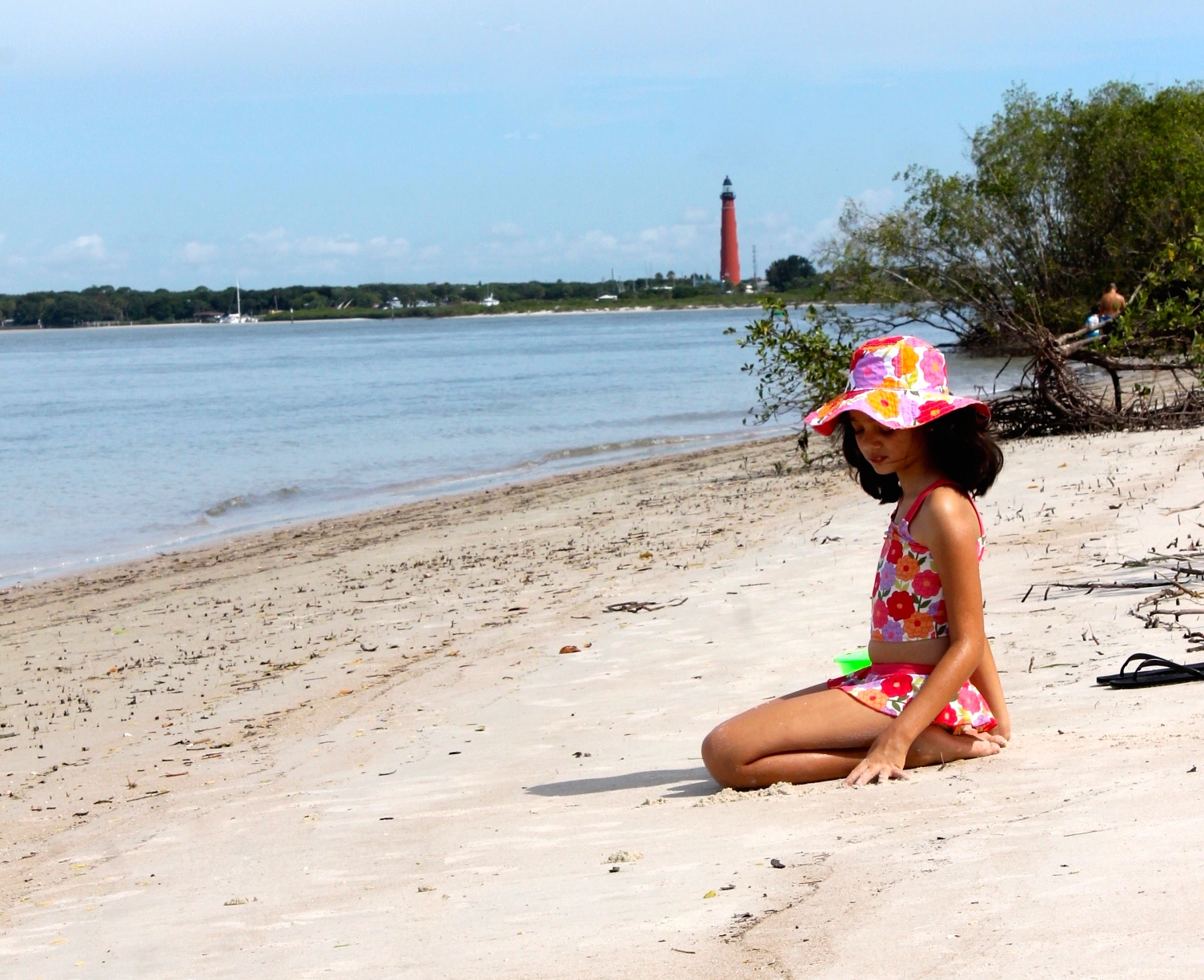 girl at the beach with lighthouse in the background at dunes park in New Smyrna beach