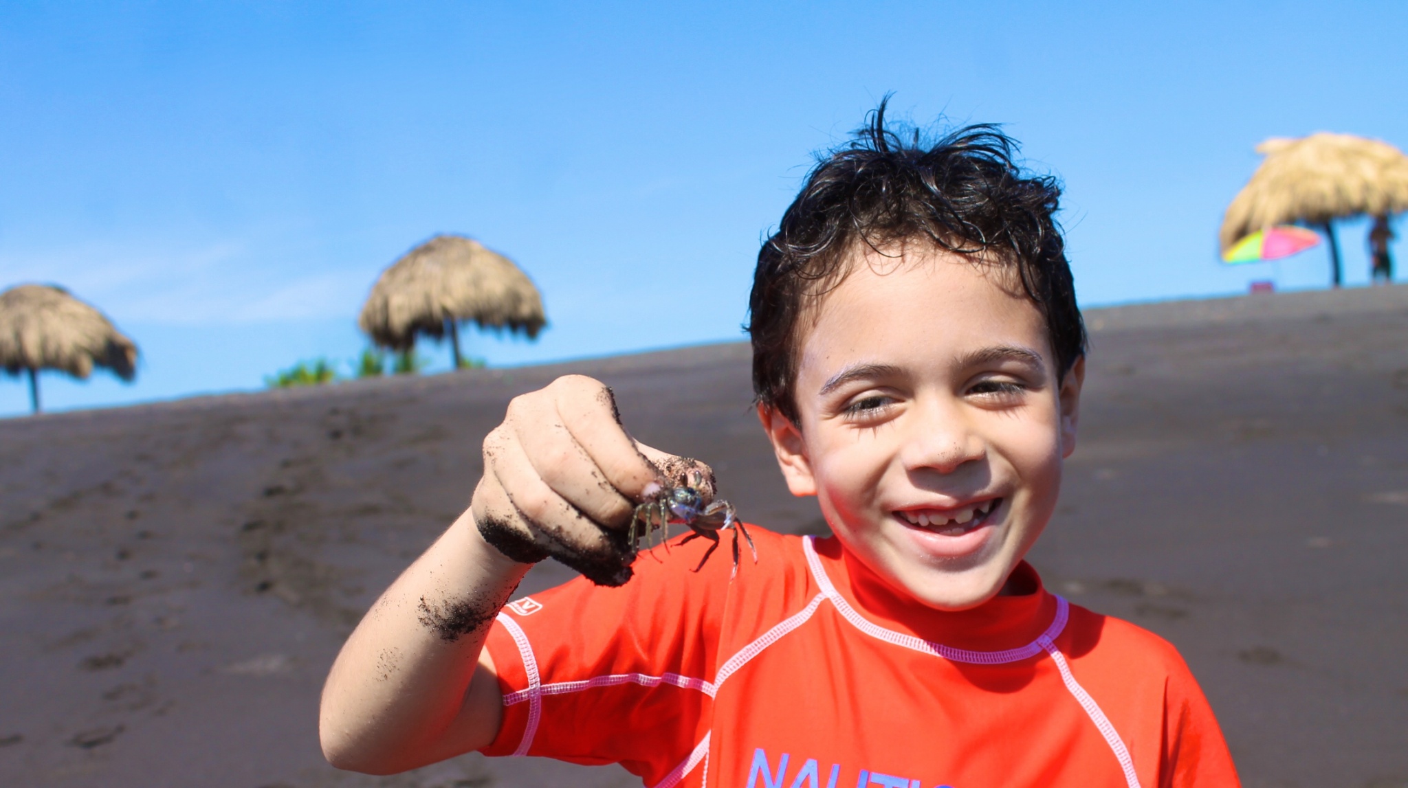 boy with crab at black sand beach in Guatemala