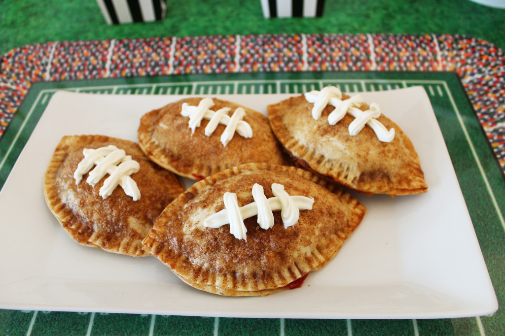 Football-shaped strawberry and chocolate empanadas made with Snickers, cream cheese laces, baked golden brown