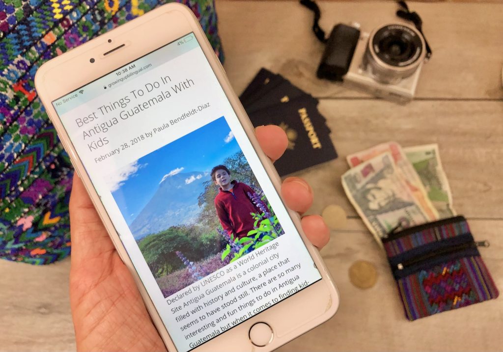 Turning a travel blog into a business with a Guatemala travel article displayed on a phone beside a camera, passport, and Guatemalan currency