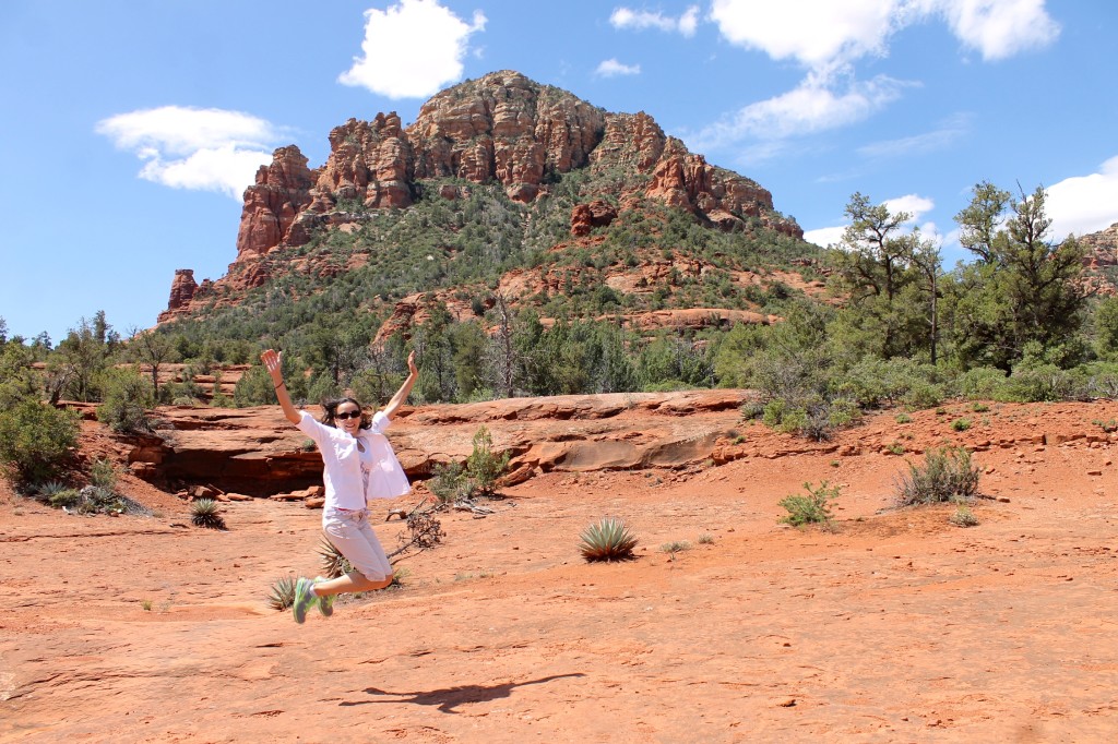woman hiker jumping for joy in Sedona red rocks