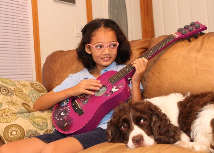girl playing guitar with dog
