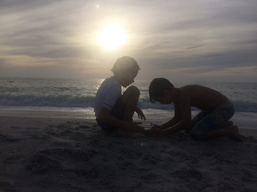 boys playing at the beach during sunset