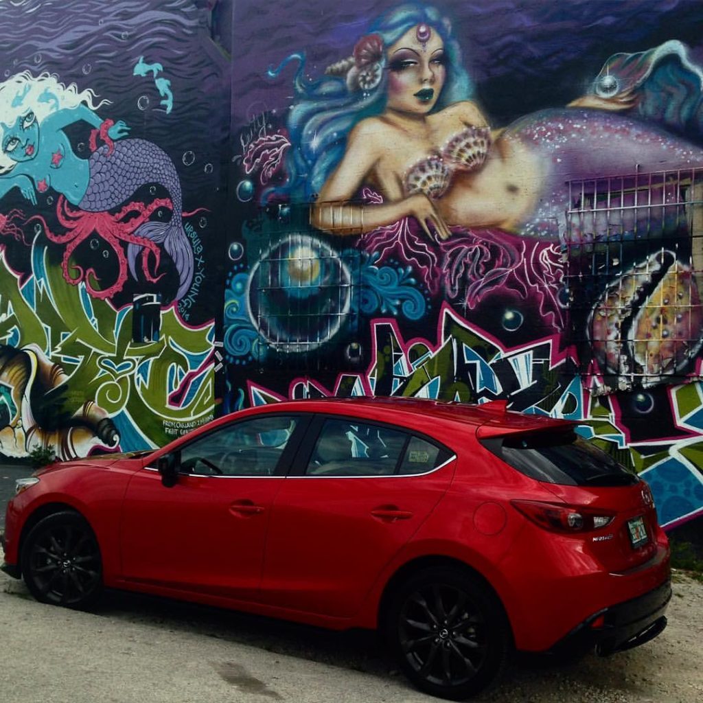 red Mazda 3 in front of street art