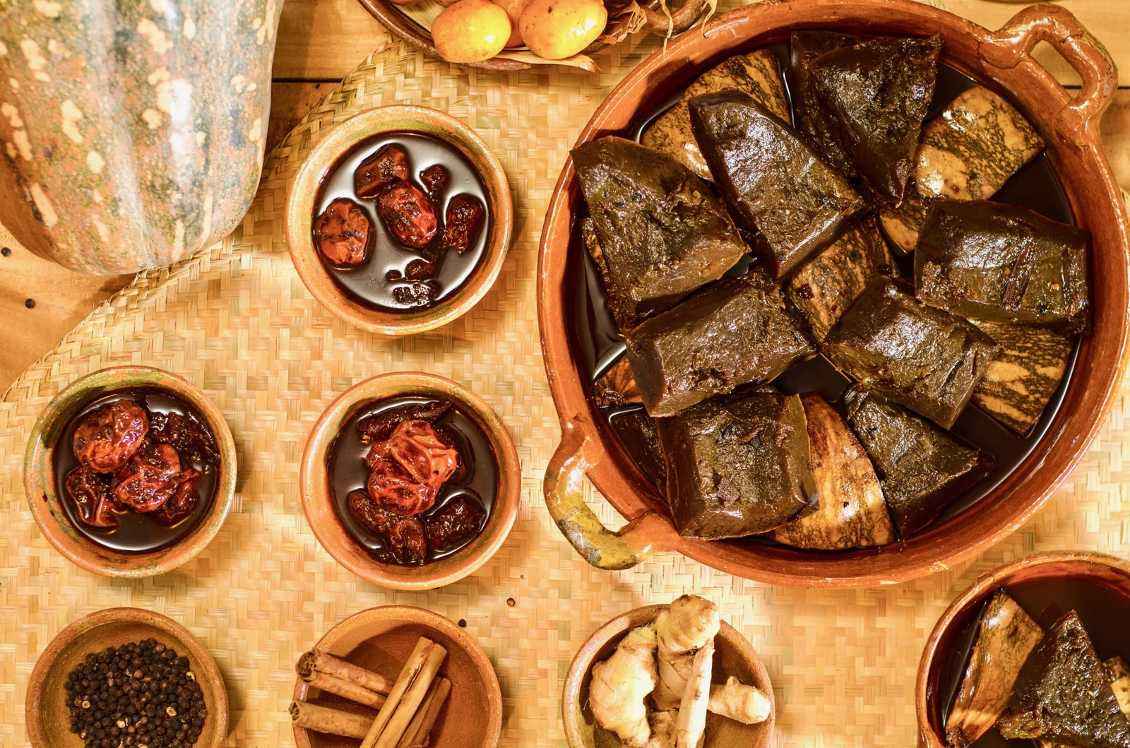 Ayote en miel in a clay pot surrounded by cinnamon, ginger, and panela