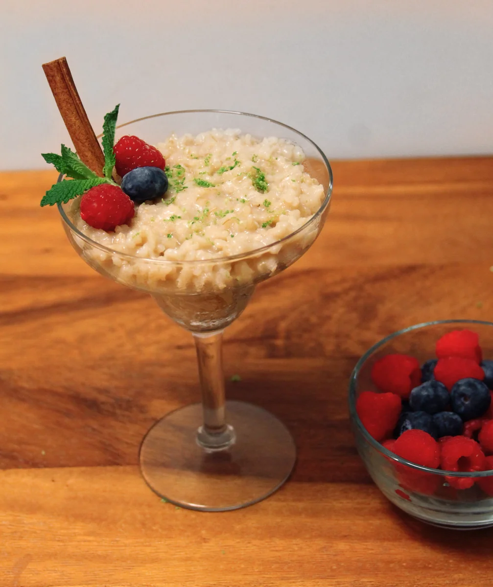 Arroz con leche guatemalteco servido en copa con canela, menta y frutos rojos 
