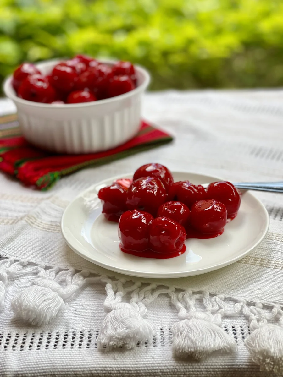Manzanillas en miel, small red apples candied in syrup, on a white plate