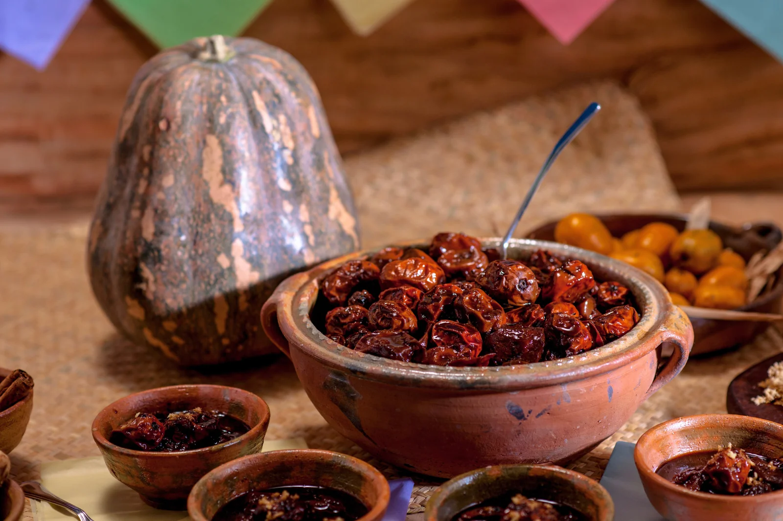 Jocotes en miel en olla de barro con papel picado para Todos los Santos