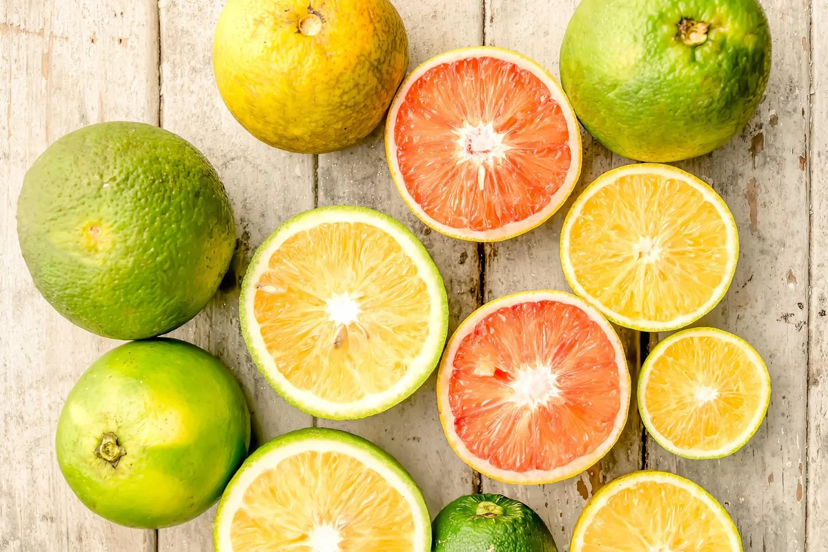 Naranjas, limones y cítricos frescos partidos por la mitad sobre madera