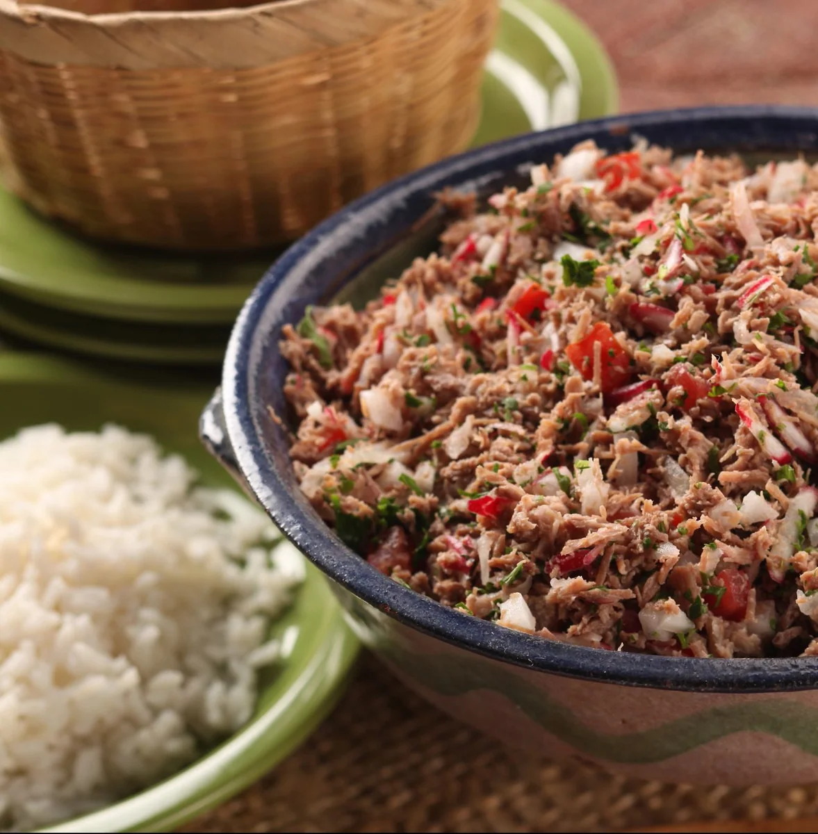 Guatemalan beef salpicón in a blue clay bowl next to a plate of white rice