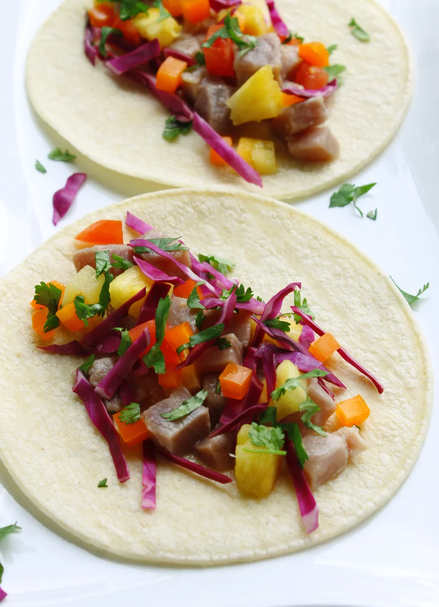 Tuna and pineapple ceviche tacos on corn tortillas with red cabbage and cilantro