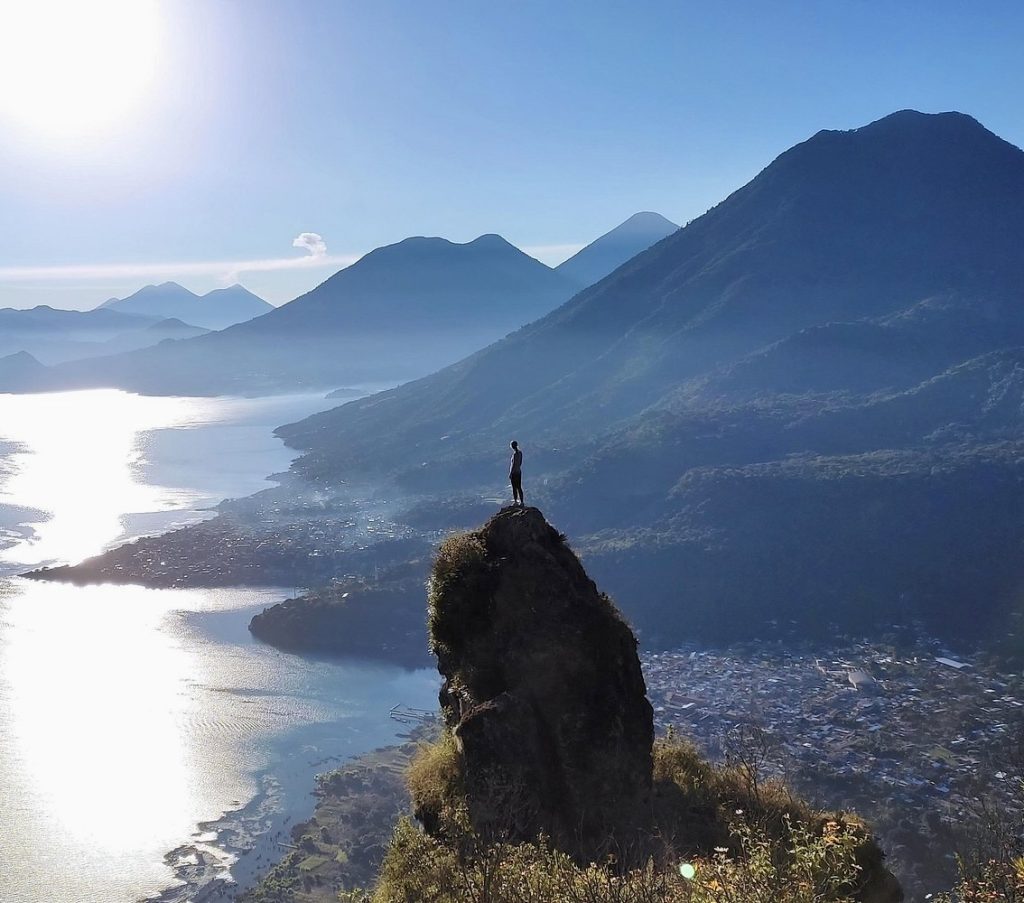 Hiker standing on a cliff overlooking Lake Atitlán during the Mayan Nose sunrise hike