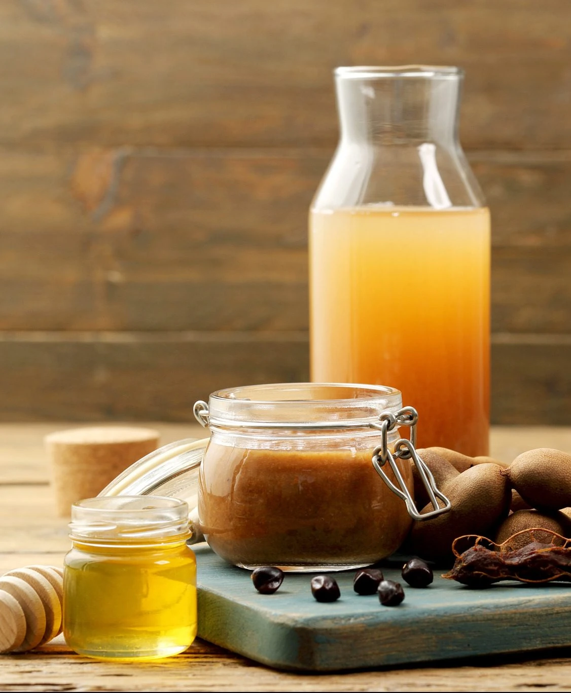 Carafe of agua de tamarindo beside a jar of homemade tamarind paste and pods