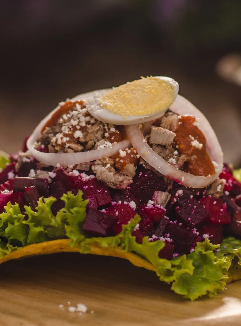 Guatemalan enchilada with beets, meat, egg, and cheese on a tostada