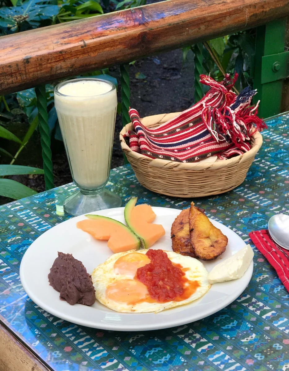 Guatemalan breakfast of huevos rancheros with platanitos fritos, refried black beans and fresh cheese