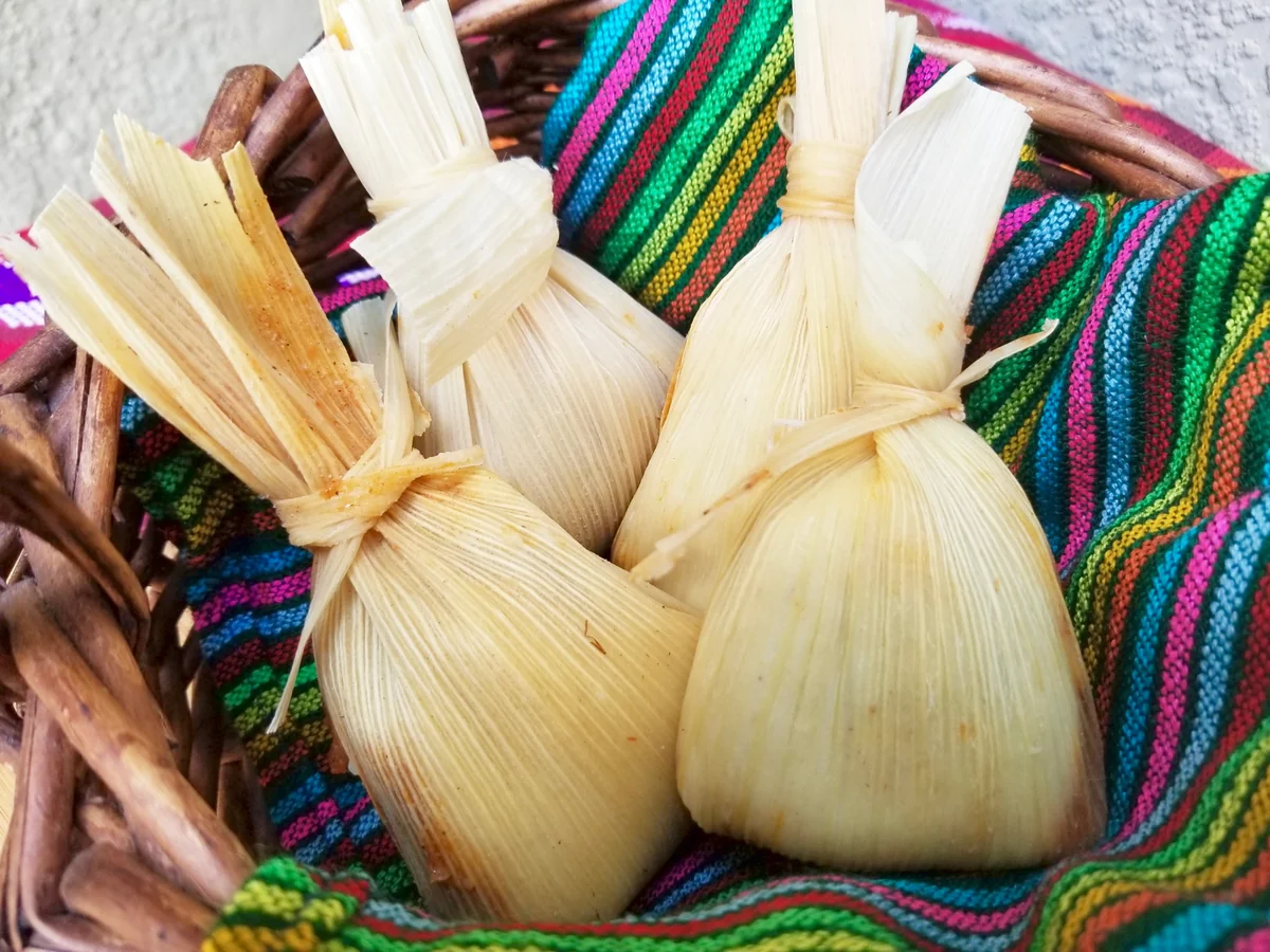 Chuchitos wrapped in corn husks in a woven basket, a Guatemalan street food