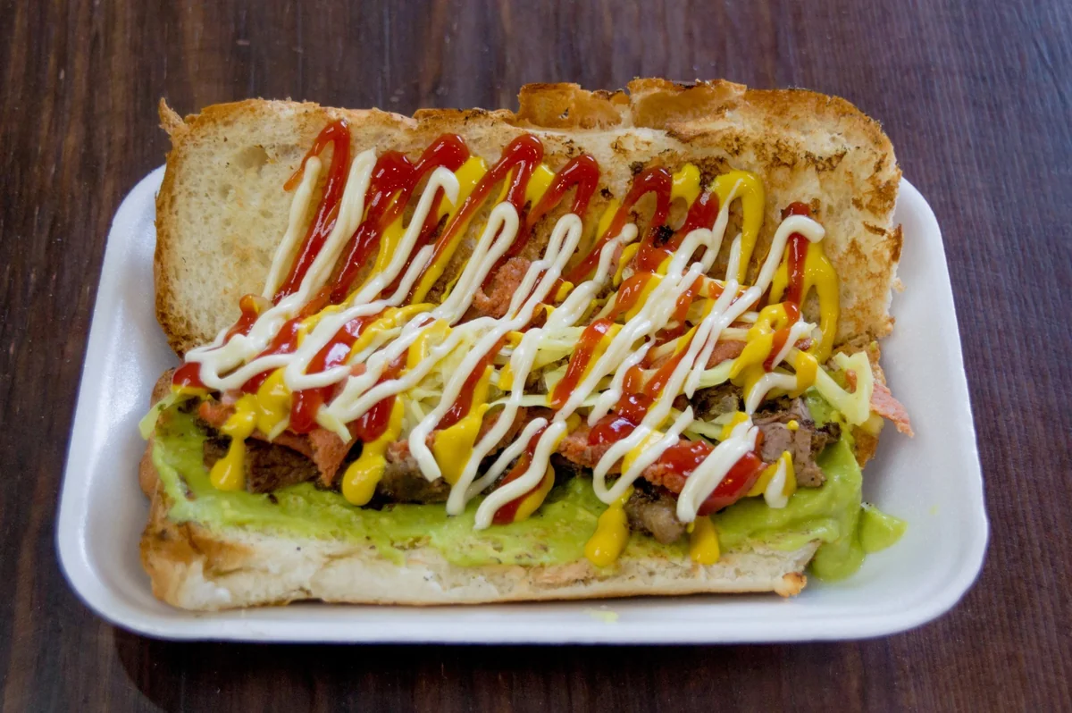 Loaded shuco Guatemalan hot dog with mustard, ketchup and guacamole on a tray