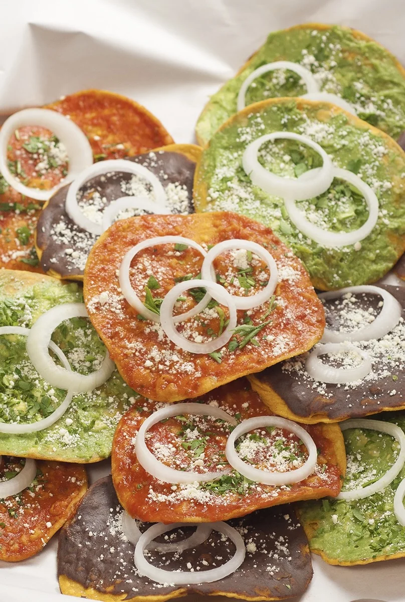 Guatemalan tostadas topped with black bean, guacamole and salsa with cheese