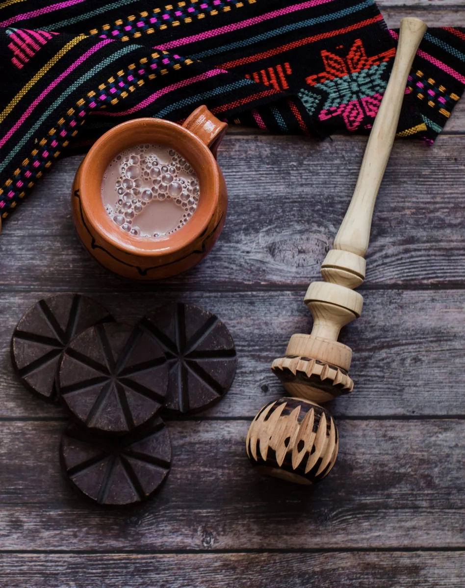 Cup of Guatemalan hot chocolate with a wooden molinillo and cacao tablets