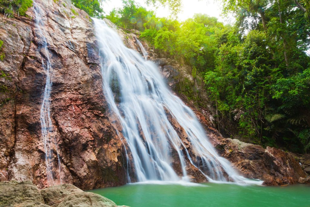 Cascading Na Muang Waterfall surrounded by green forest on the island of Koh Samui in Thailand.