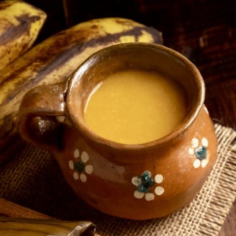 Plantain atole in traditional Guatemalan mug with ripe plantains