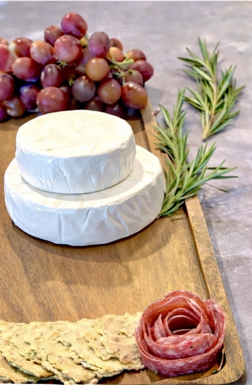 This brie cake base is the starting point for a cranberry brie cake grazing board. Stacked brie wheels create an elegant cheese centerpiece that works perfectly for holiday grazing boards, Christmas charcuterie boards, and simple entertaining.