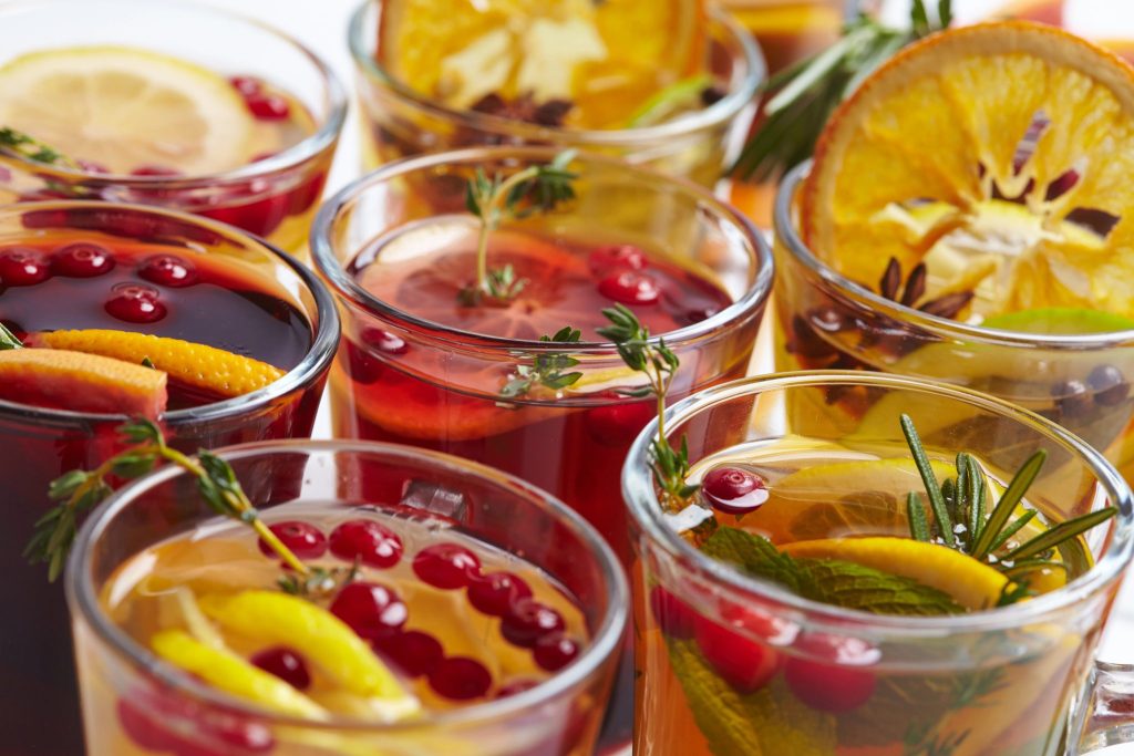 Close-up of winter cocktails including mulled wine and spiced punches with cranberries, citrus, and herbs