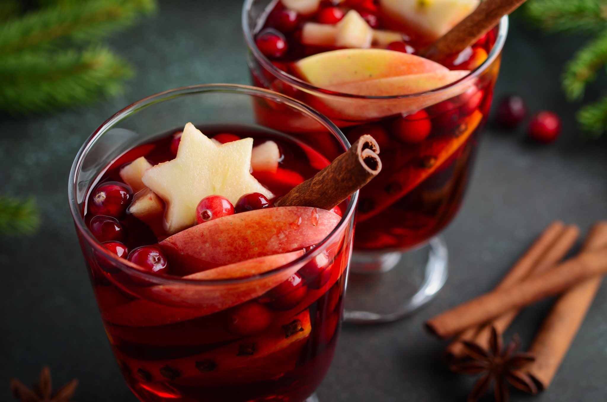 Holiday mulled wine with cranberries, cinnamon, and orange slices in glass mugs