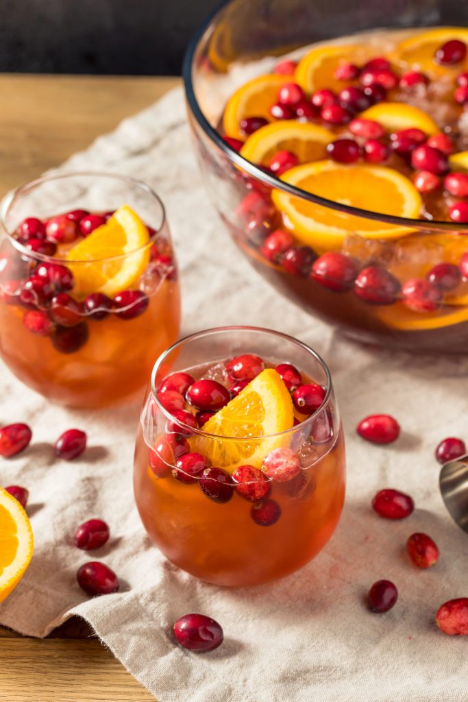 Holiday cranberry champagne punch served in glasses with orange slices