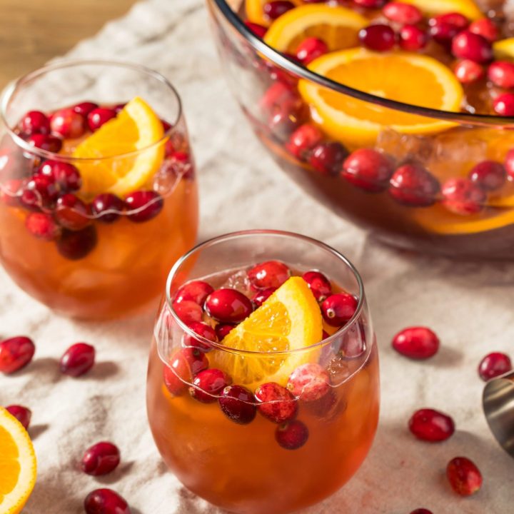 Holiday cranberry champagne punch served in glasses with orange slices