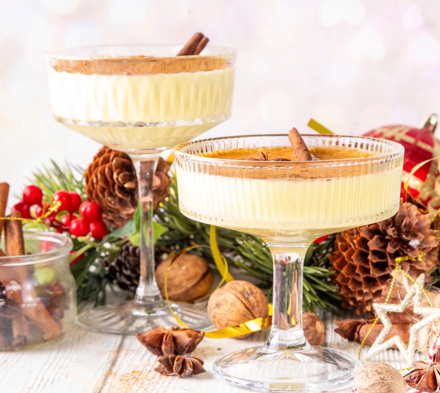 Eggnog martinis on a festive holiday table with pinecones and ornaments