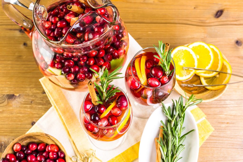 Cranberry sangria served in glasses with fresh cranberries, orange slices, and rosemary