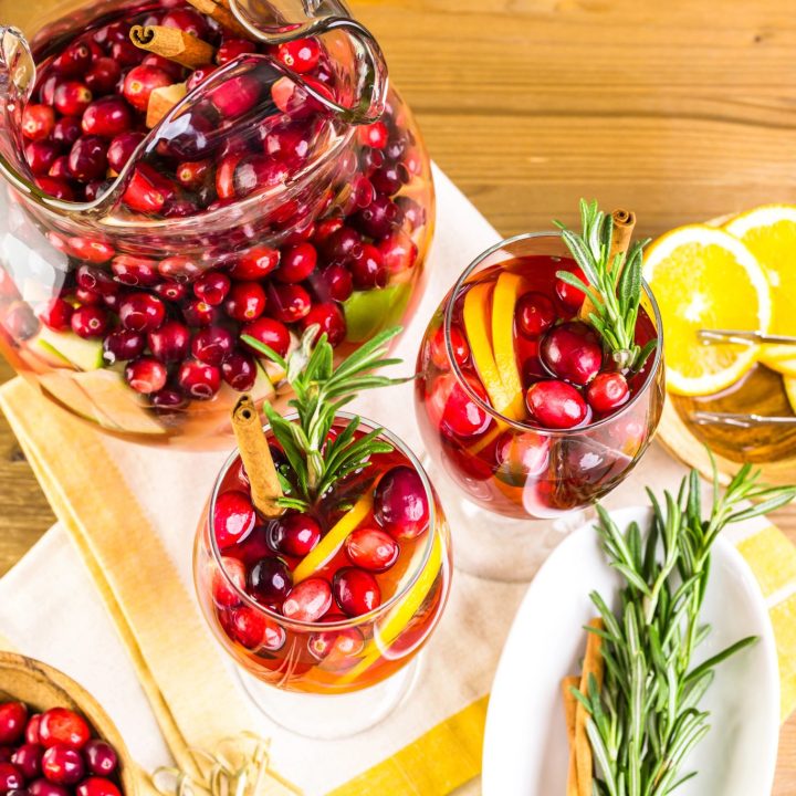 Cranberry sangria served in glasses with fresh cranberries, orange slices, and rosemary
