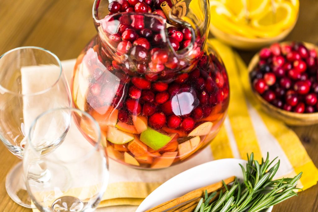 Cranberry sangria in a glass pitcher with fresh fruit for holiday entertaining