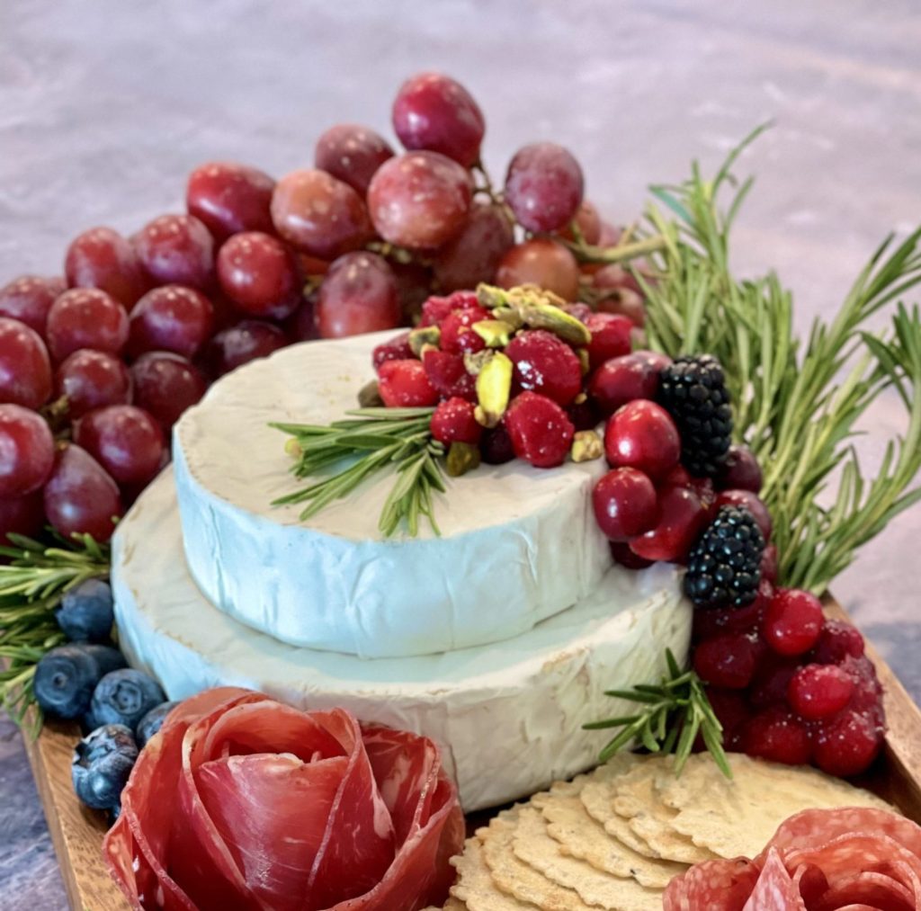 This holiday brie cake topped with cranberries and pistachios makes a beautiful and simple centerpiece for a Christmas charcuterie board or holiday grazing board. No baking required and perfect for entertaining.