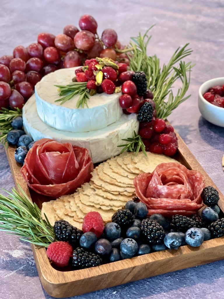 This cranberry brie cake grazing board is an elegant holiday cheese centerpiece made with stacked brie wheels, cranberries, pistachios, and rosemary. A simple but stunning brie cake charcuterie board idea perfect for Christmas entertaining, holiday parties, and grazing tables.
