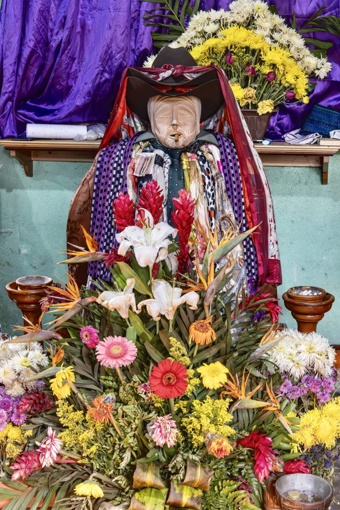 Maximón — the Rilaj Mam — seated in his chapel surrounded by flower offerings during Holy Week in Santiago Atitlán, Guatemala