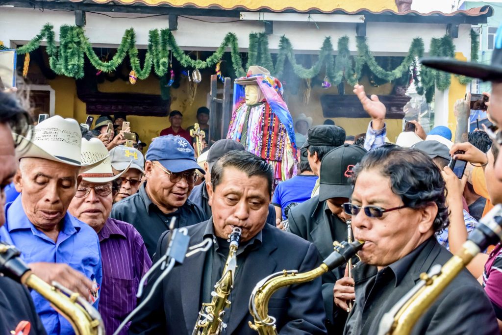 Maximón carried through the crowded streets of Santiago Atitlán accompanied by a brass band during his Holy Wednesday procession — Semana Santa traditions in Santiago Atitlán, Guatemala