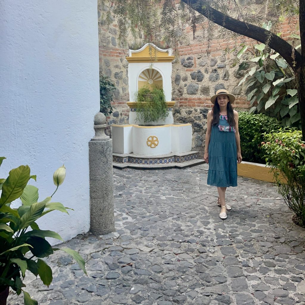 Patio empedrado con fuente colonial en Villa Colonial, hotel boutique en Antigua Guatemala, con paredes de piedra y vegetación